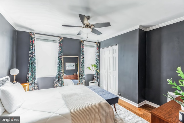 bedroom with crown molding, a closet, ceiling fan, wood finished floors, and baseboards