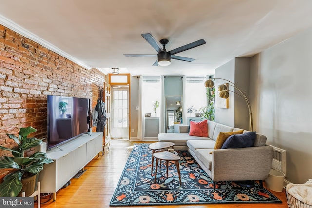 living room with brick wall, ceiling fan, and light hardwood / wood-style flooring