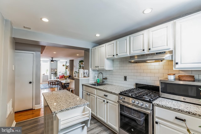 kitchen with under cabinet range hood, appliances with stainless steel finishes, white cabinets, and a sink