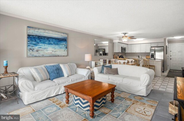 living room with tile patterned flooring, ceiling fan, a textured ceiling, and crown molding