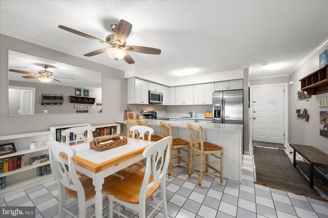 dining space with a textured ceiling, ceiling fan, light tile patterned floors, and crown molding