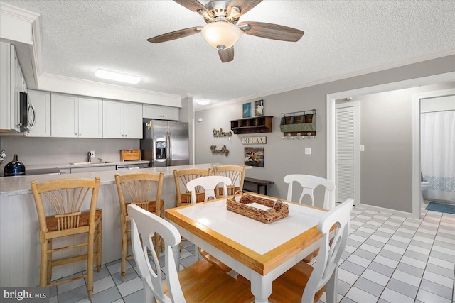 dining space with ceiling fan, ornamental molding, a textured ceiling, and light tile patterned flooring