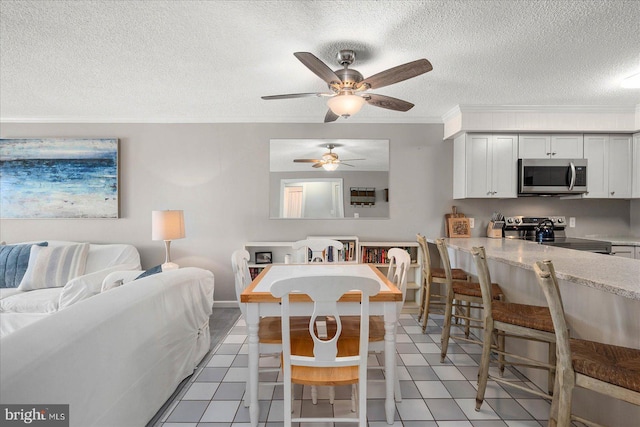 dining room featuring light tile patterned floors, ornamental molding, a textured ceiling, and a ceiling fan