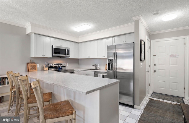 kitchen featuring a peninsula, a sink, stainless steel appliances, and light countertops