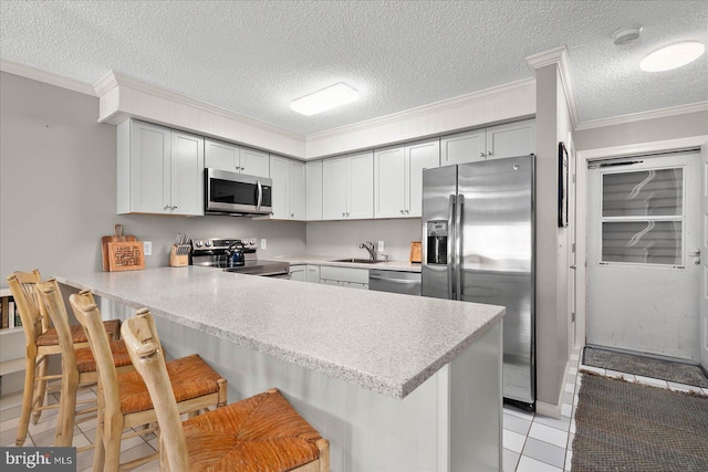 kitchen with appliances with stainless steel finishes, a breakfast bar, ornamental molding, and kitchen peninsula