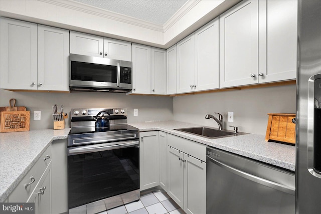 kitchen featuring a textured ceiling, light stone counters, stainless steel appliances, a sink, and ornamental molding