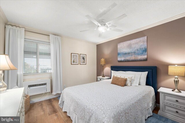 bedroom with light hardwood / wood-style floors, ornamental molding, ceiling fan, and an AC wall unit