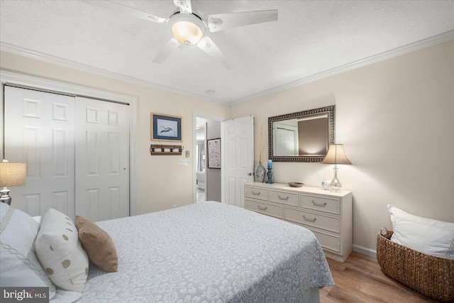 bedroom with a textured ceiling, a ceiling fan, ornamental molding, a closet, and light wood finished floors