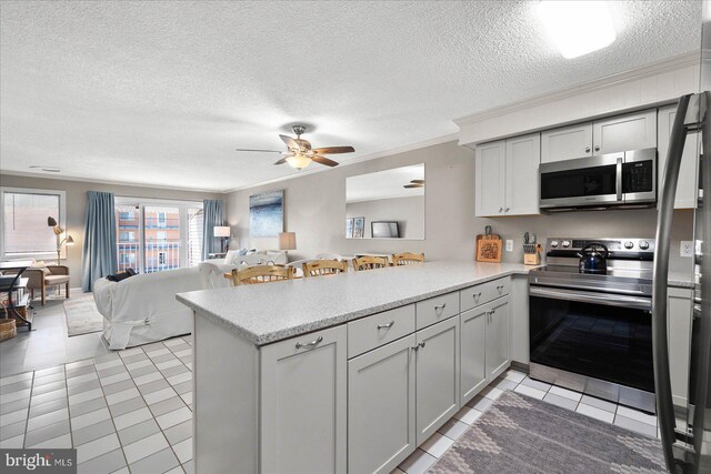 kitchen featuring light tile patterned flooring, stainless steel appliances, ceiling fan, crown molding, and kitchen peninsula