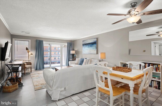 living room with ceiling fan, ornamental molding, a textured ceiling, and light tile patterned floors