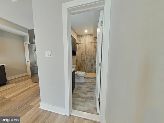 corridor with light hardwood / wood-style flooring and wooden walls