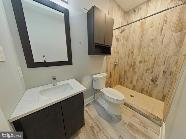 bathroom with vanity, hardwood / wood-style floors, a tile shower, and toilet