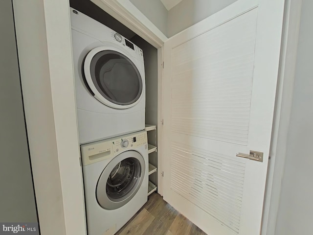 laundry area featuring stacked washer / dryer and wood-type flooring