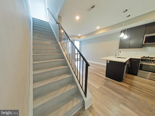 stairs featuring a healthy amount of sunlight, wood-type flooring, and sink