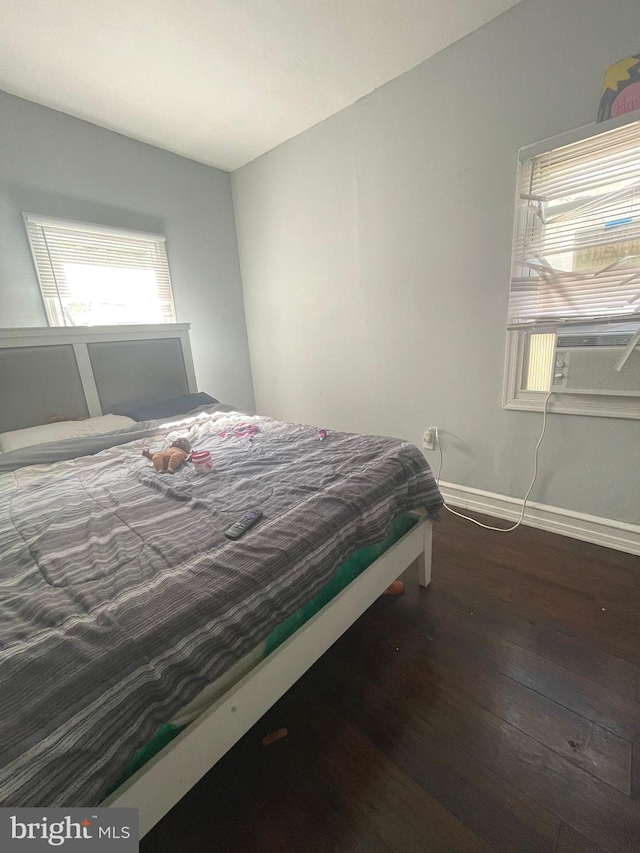 bedroom featuring cooling unit, baseboards, and wood finished floors