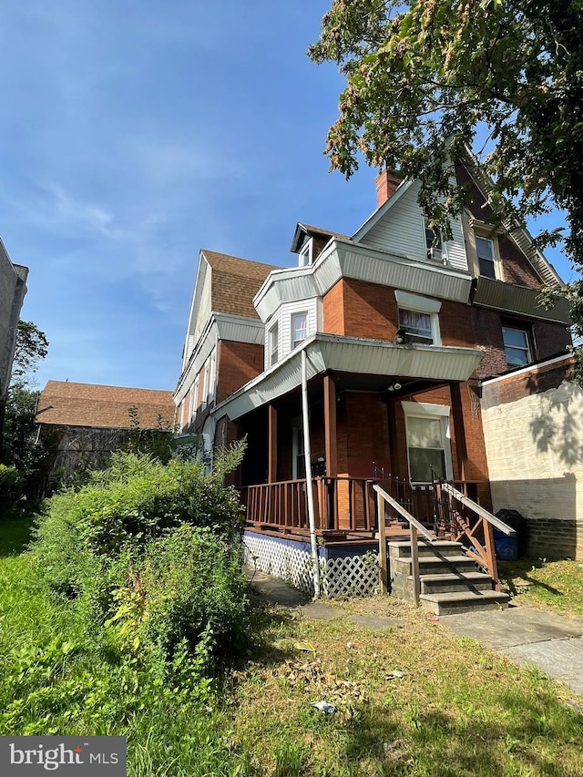 view of front facade featuring a chimney and a porch