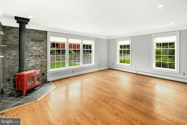 unfurnished living room featuring a baseboard heating unit, ornamental molding, wood finished floors, and a wood stove