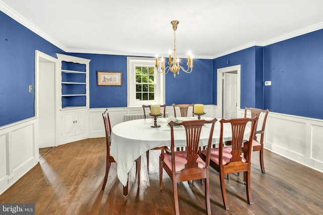 dining space with ornamental molding, dark wood-style flooring, a wainscoted wall, and a notable chandelier