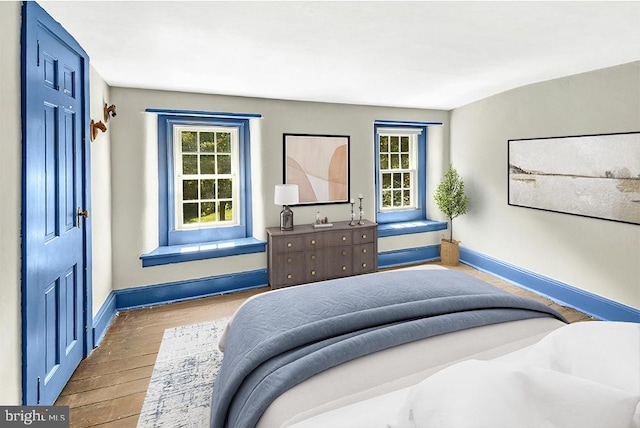 bedroom featuring multiple windows, baseboards, and wood finished floors