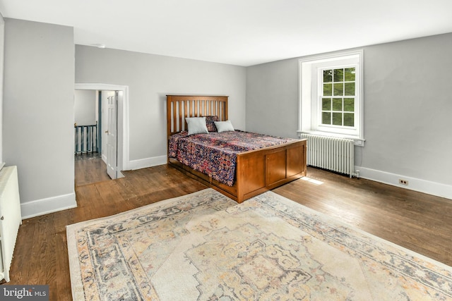 bedroom with baseboards, dark wood finished floors, and radiator heating unit