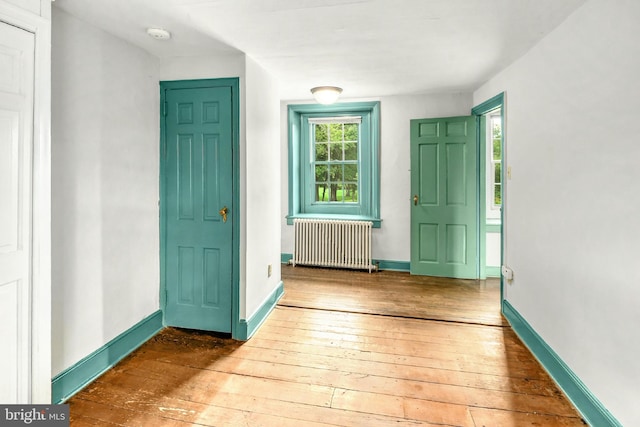 entrance foyer with radiator, baseboards, and wood finished floors