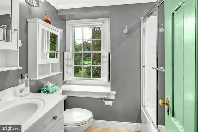 bathroom featuring baseboards, bath / shower combo with glass door, toilet, crown molding, and vanity