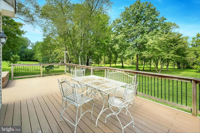 wooden terrace featuring outdoor dining area and a yard