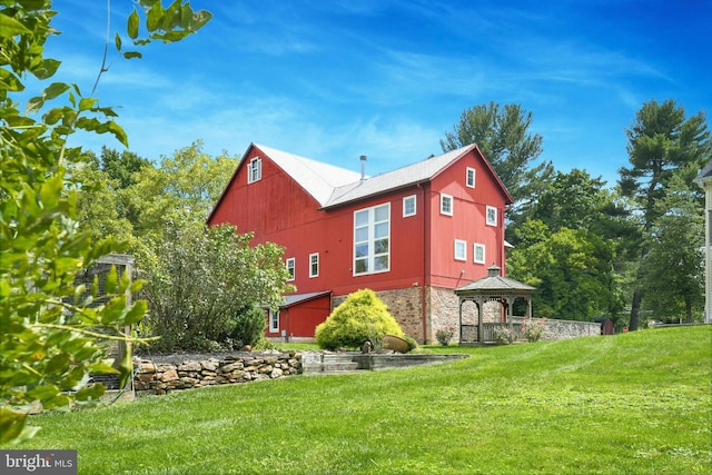 view of property exterior featuring a yard, stone siding, and a gazebo