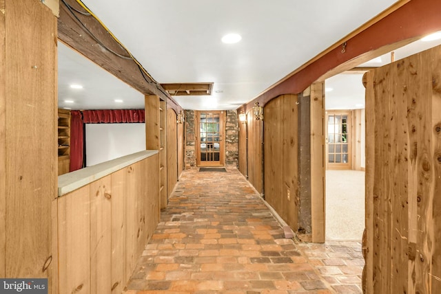 corridor with wood walls and brick floor