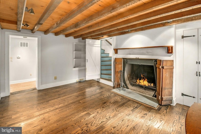 unfurnished living room featuring visible vents, wood ceiling, wood finished floors, beamed ceiling, and a lit fireplace