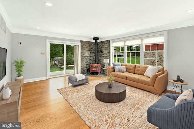 living room with recessed lighting, ornamental molding, a wood stove, wood finished floors, and baseboards