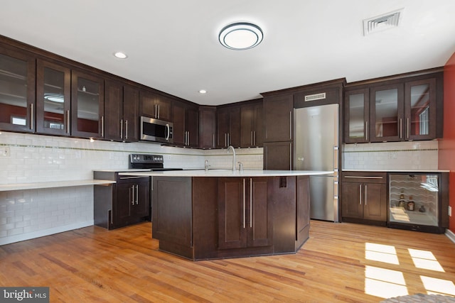 kitchen with tasteful backsplash, light hardwood / wood-style flooring, and appliances with stainless steel finishes