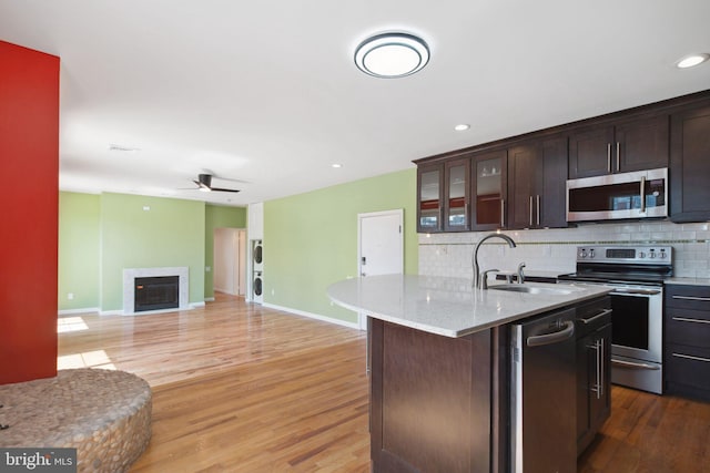 kitchen featuring ceiling fan, decorative backsplash, light hardwood / wood-style floors, and stainless steel appliances