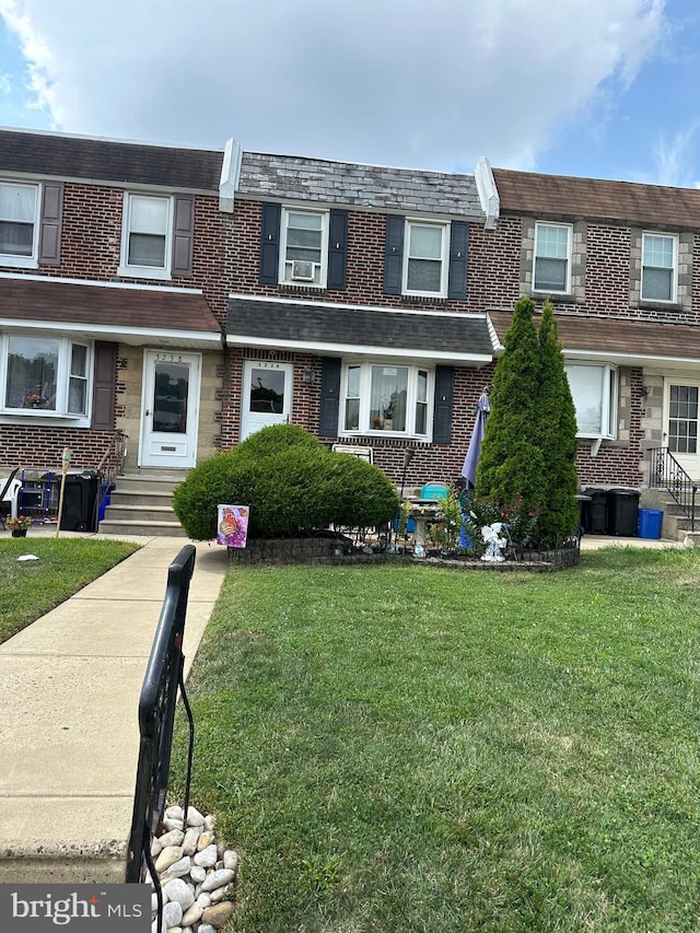 view of property with a shingled roof, cooling unit, brick siding, and a front lawn