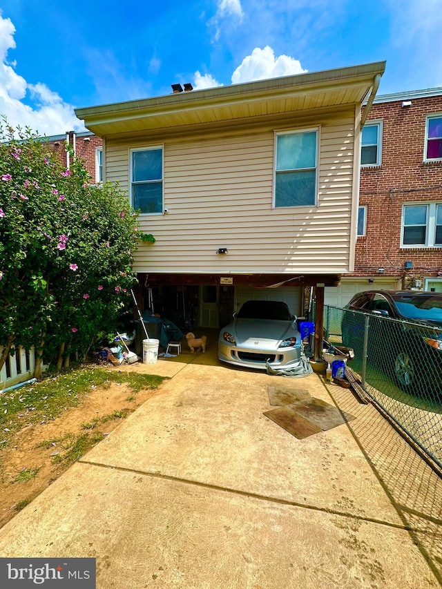 back of property featuring driveway, fence, and a carport