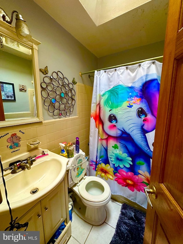 bathroom featuring backsplash, tile patterned floors, vanity, tile walls, and toilet