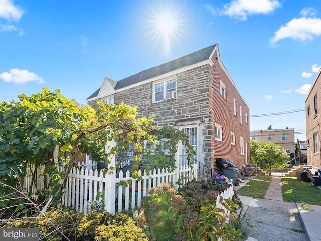 view of front of home with stone siding and fence