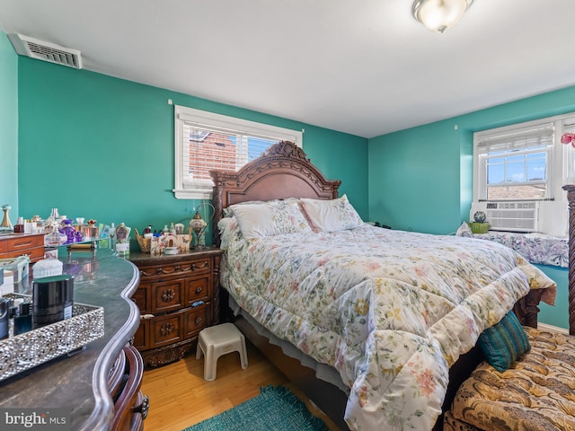 bedroom featuring wood-type flooring, multiple windows, and cooling unit