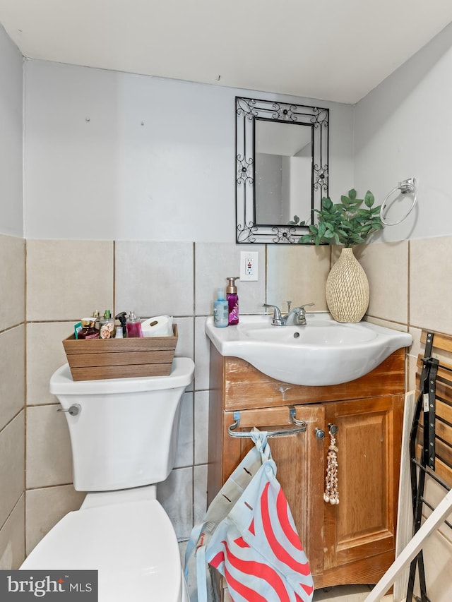 bathroom featuring vanity, toilet, and tile walls