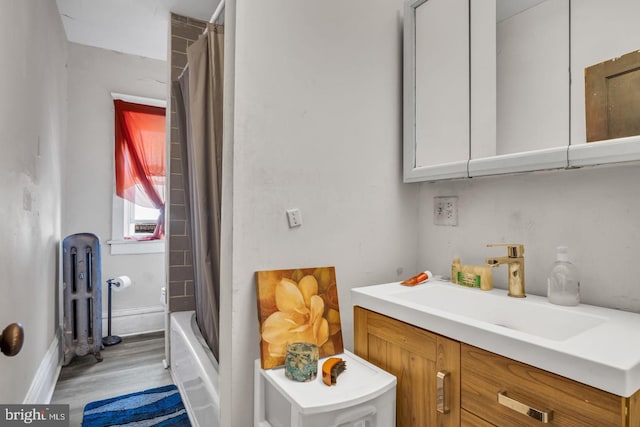 interior space featuring radiator, shower / bathtub combination with curtain, vanity, and wood finished floors