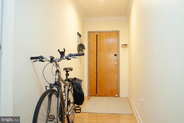 doorway featuring light wood finished floors, baseboards, and ornamental molding