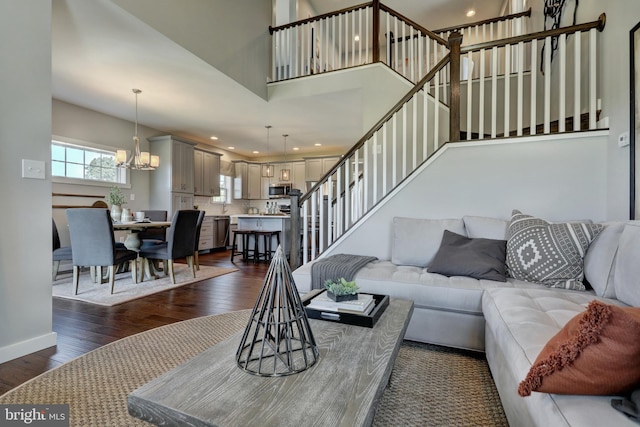 living room featuring a chandelier, dark hardwood / wood-style floors, and a towering ceiling