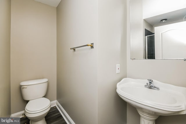 bathroom featuring wood finished floors, a sink, toilet, and baseboards