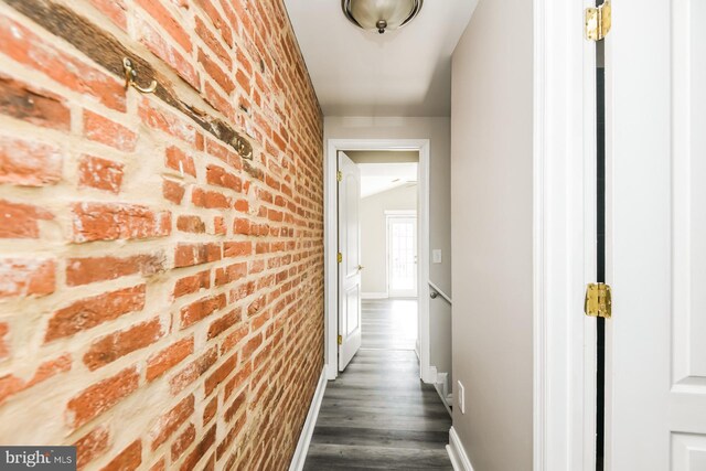 hall featuring brick wall and dark hardwood / wood-style flooring