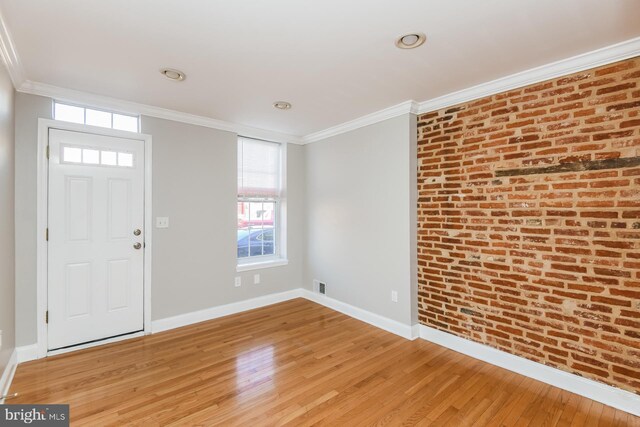 foyer entrance featuring brick wall, hardwood / wood-style floors, and ornamental molding