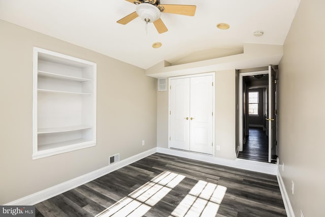 unfurnished bedroom with lofted ceiling, ceiling fan, visible vents, baseboards, and dark wood finished floors