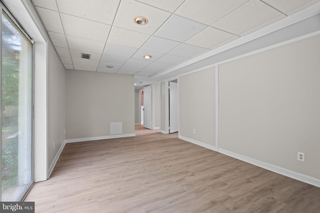 empty room with light hardwood / wood-style flooring and a paneled ceiling