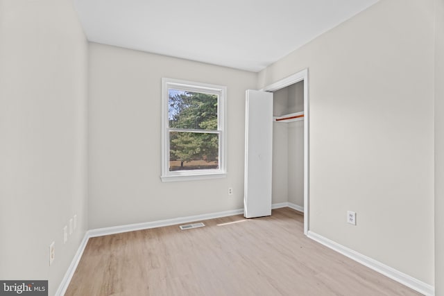 unfurnished bedroom with light wood-type flooring and a closet