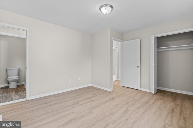 unfurnished bedroom with light hardwood / wood-style floors and connected bathroom