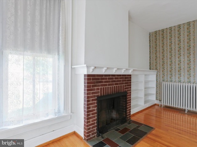 unfurnished living room featuring hardwood / wood-style floors, a fireplace, and radiator heating unit